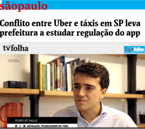 PrintScreen do reportagem da Folha de São Paulo. No título, lê-se: Conflito entre Uber e táxis em SP leva prefeitura estudar regulação do app. Em baixo, há uma imagem do Pedro. Ele é branco, cabelos curtos castanhos e está com os lábios fechados. Usa uma camisa social branca, e está atrás de uma estante de livros. 